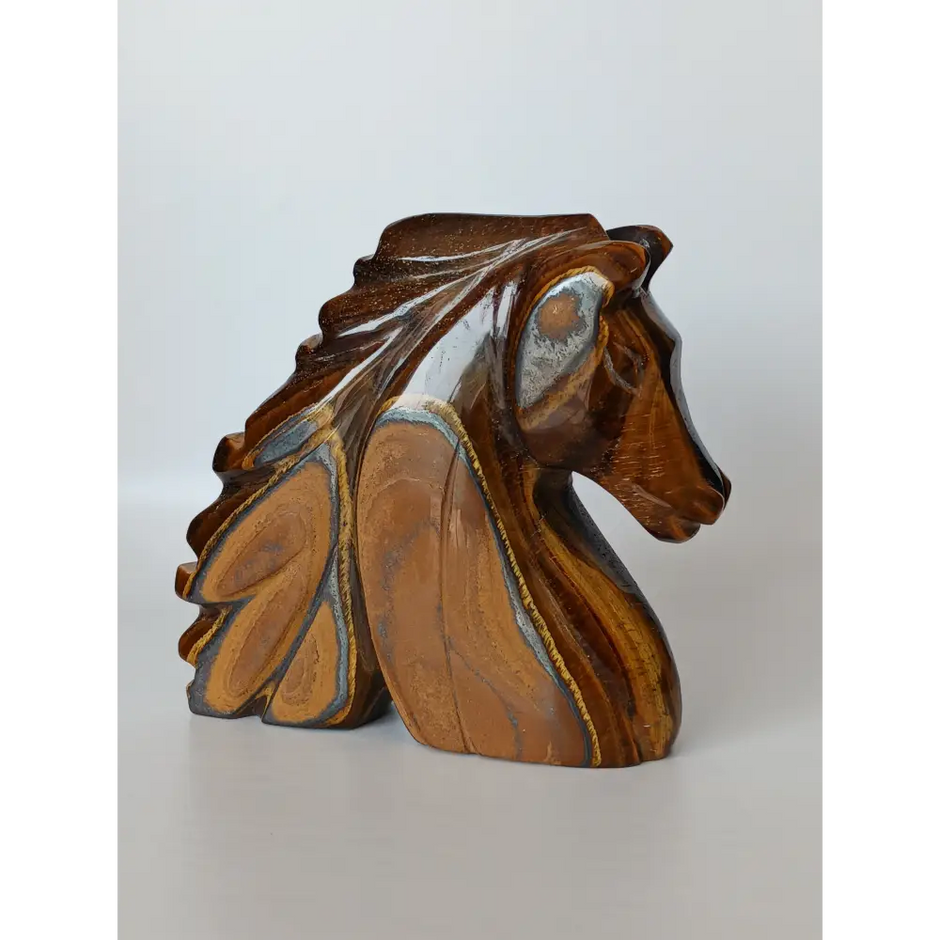 Assorted hand-carved animal figurines made from Blue Tiger’s Eye, Fluorite, and Tiger’s Eye crystals, each featuring unique colors and patterns, displayed on a white background.