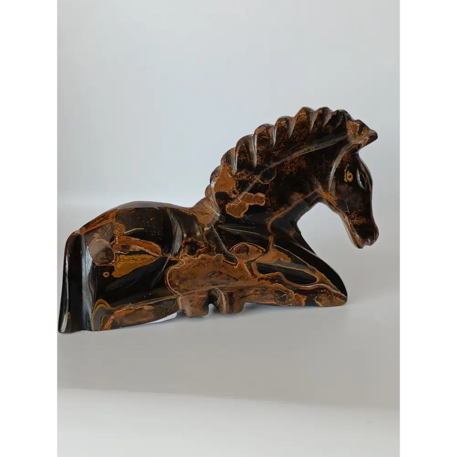 Assorted hand-carved animal figurines made from Blue Tiger’s Eye, Fluorite, and Tiger’s Eye crystals, each featuring unique colors and patterns, displayed on a white background.