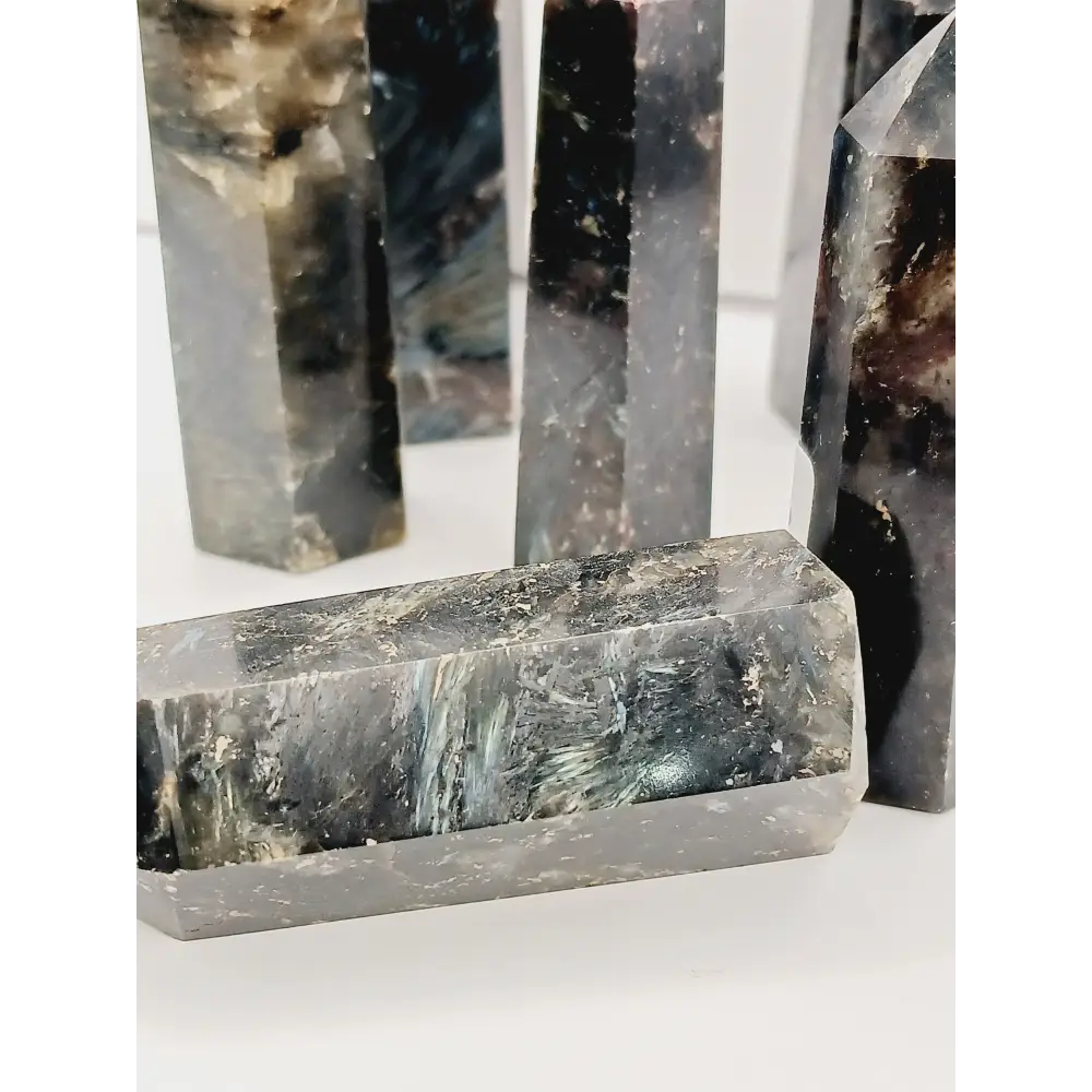 Astrophyllite (firework stone) with garnet tower, 2.5–3 inches, hand-polished with golden flashes and deep red inclusions, displayed on a white background.