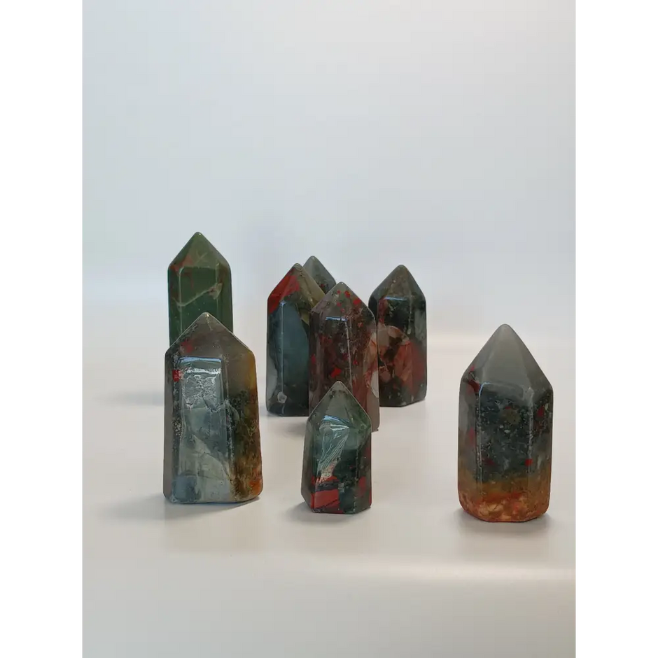 Hand-carved Bloodstone point, 2 to 2.5 inches tall, featuring deep green with natural red flecks, displayed on a white background.

