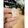 Hand-carved 1 1/2 inch tall Buddha head figurines in assorted crystal materials such as amethyst, rose quartz, clear quartz, and jade, displayed on a white background.