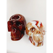Carnelian skull with vibrant orange-red hues and natural banding, carved and displayed on a white background.