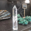 Hand-carved Clear Quartz tower featuring brilliant transparency and natural inclusions, displayed on a white background.