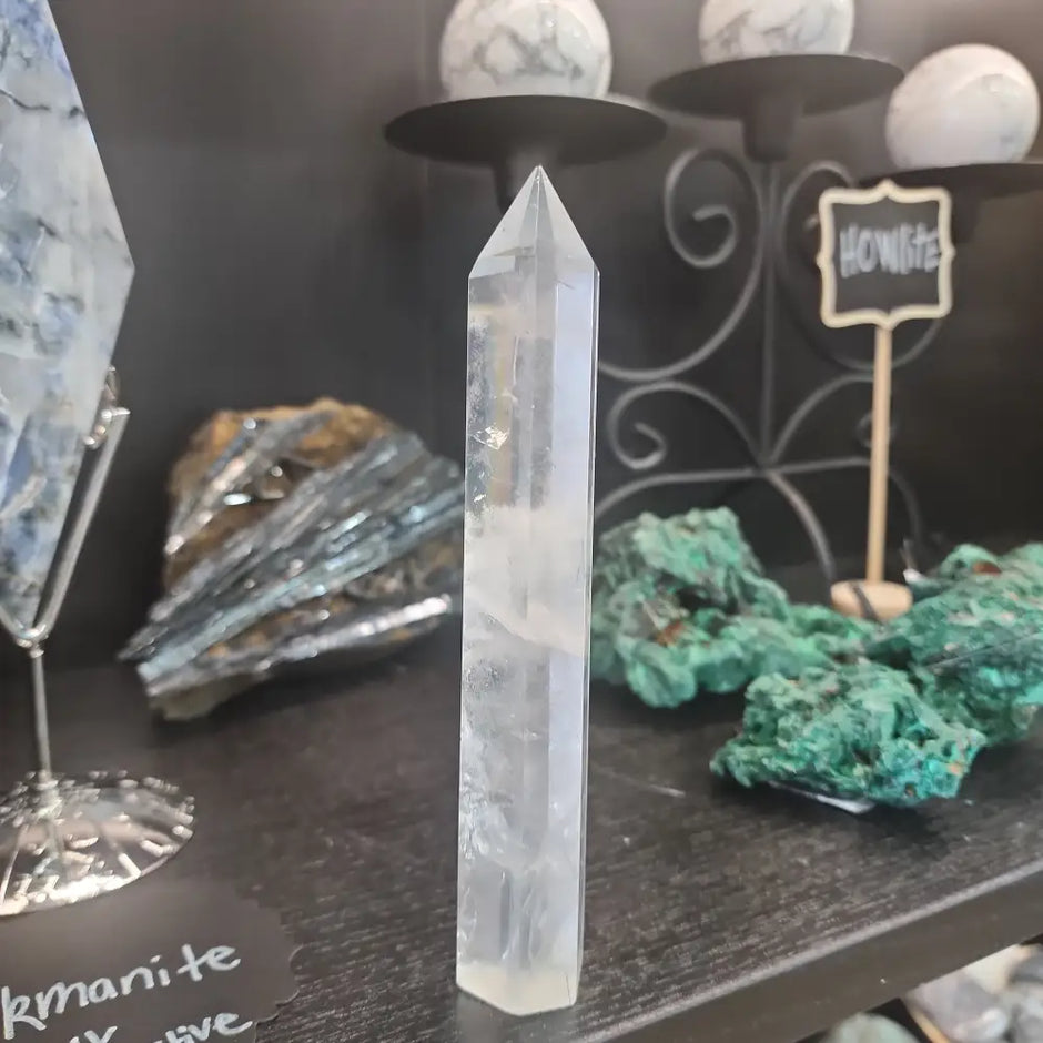 Hand-carved Clear Quartz tower featuring brilliant transparency and natural inclusions, displayed on a white background.