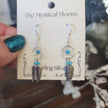 Sterling silver earrings featuring an intricate dreamcatcher with two feather charms, displayed on a white background. Perfect for protection, inspiration, and boho spirit.