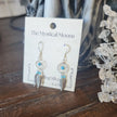 Sterling silver earrings featuring an intricate dreamcatcher with two feather charms, displayed on a white background. Perfect for protection, inspiration, and boho spirit.