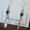 Sterling silver feather earrings featuring vibrant malachite stones, displayed on a white background. Perfect for transformation, protection, and spiritual freedom.