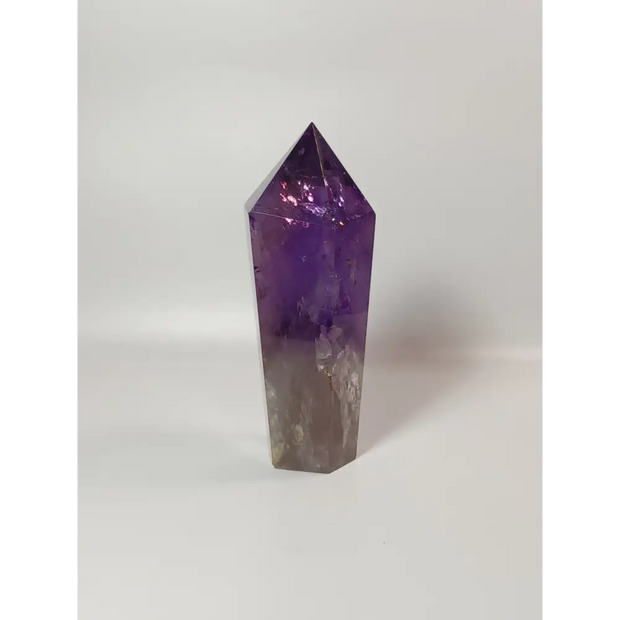 Polished freestanding Amethyst wand with deep purple hues and natural clarity, displayed on a white background.