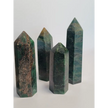 Hand-polished Green Zoisite stone featuring vibrant green hues, sometimes with black or ruby inclusions, displayed on a white background.