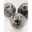 Quartz, garnet, tourmaline, and mica sphere, polished with clear, red, black, and shimmering inclusions, displayed on a white background.
