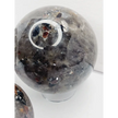 Quartz, garnet, tourmaline, and mica sphere, polished with clear, red, black, and shimmering inclusions, displayed on a white background.