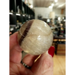 Hand-polished Rainbow and Clear Fluorite sphere featuring luminous bands of purple, green, blue, and clear tones, displayed on a white background.