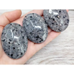 Hand-polished Yooperlite palmstone, glowing with vibrant orange and yellow patterns under UV light, displayed on a white background. Perfect for creativity, transformation, and mystical energy.